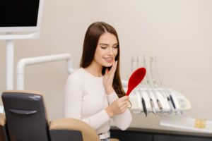 compressed pretty girl smiling while sitting dentists chair holding mirror her hands 2048x1365 1