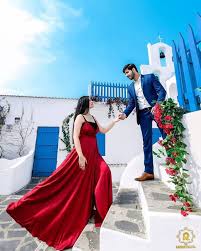 A couple poses for a romantic pre-wedding photoshoot on whitewashed stairs with blue doors and railings, inspired by Santorini architecture.