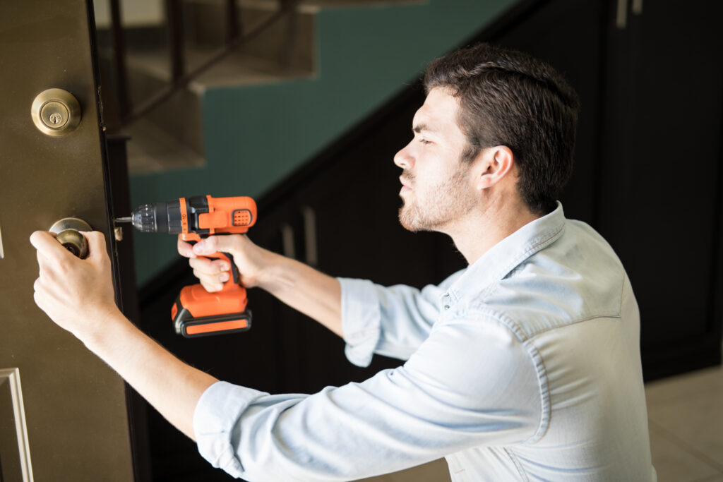 profile view attractive handyman using power drill fix door knob house